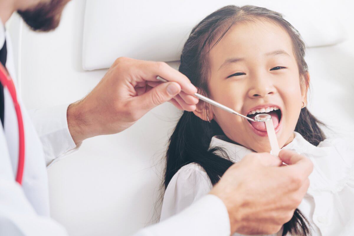 Dentist Examining Smiling Child's Teeth