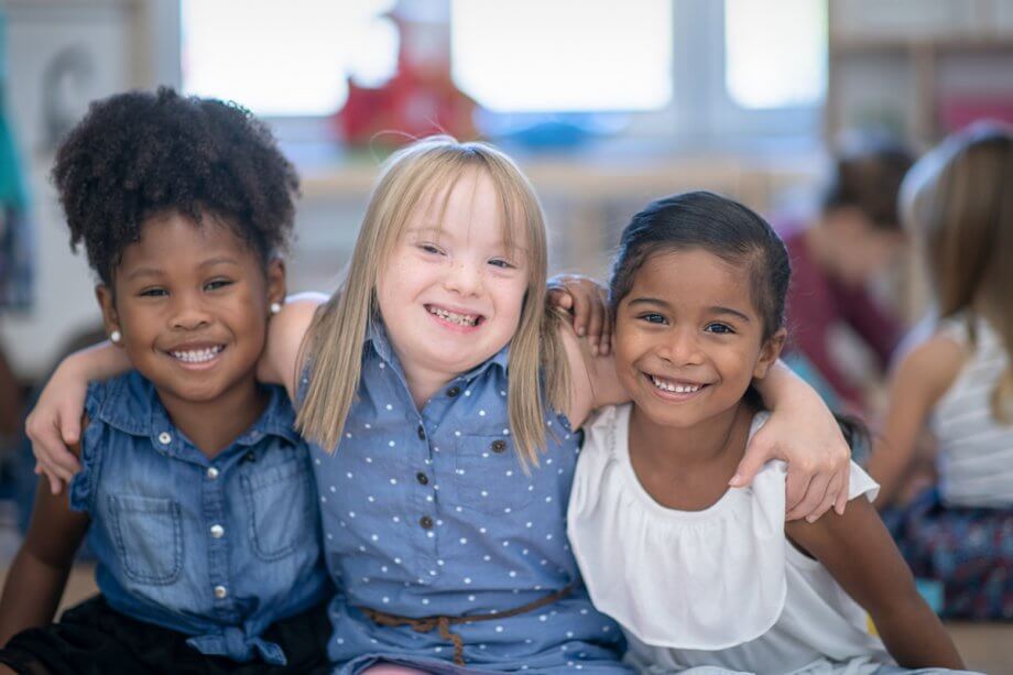 Three young girls smiling with their arms around each other