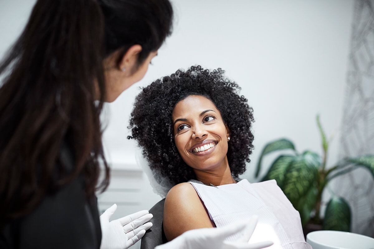 woman in dental chair smiling up at dentist