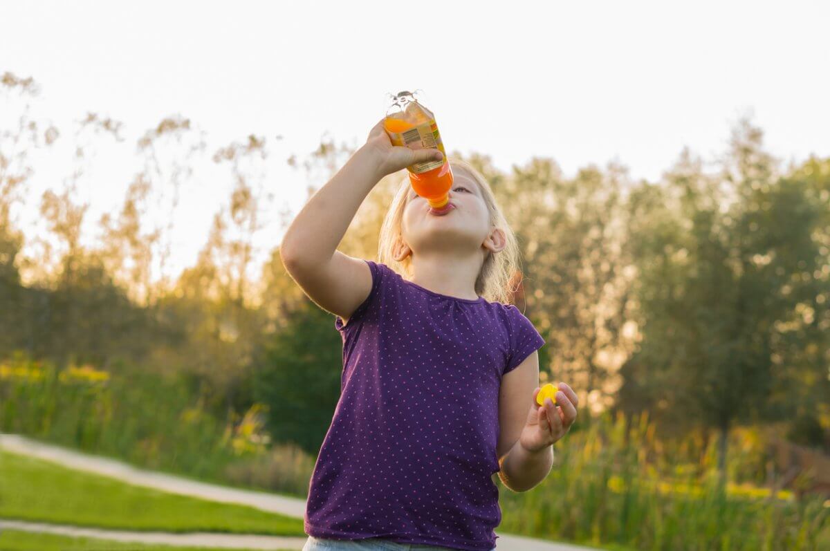 Young girl drinks juice from bottle