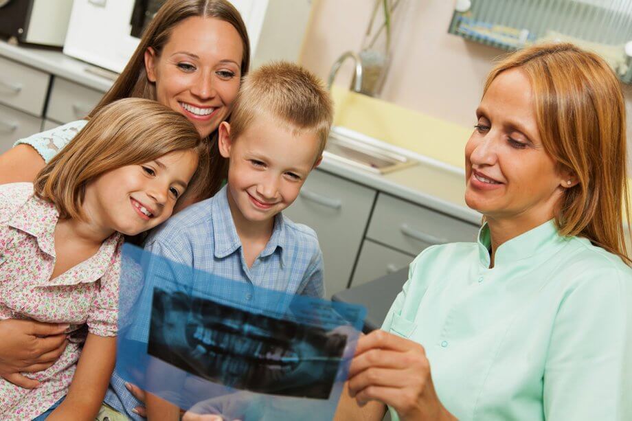 dentist showing an x-ray to a mom and two children
