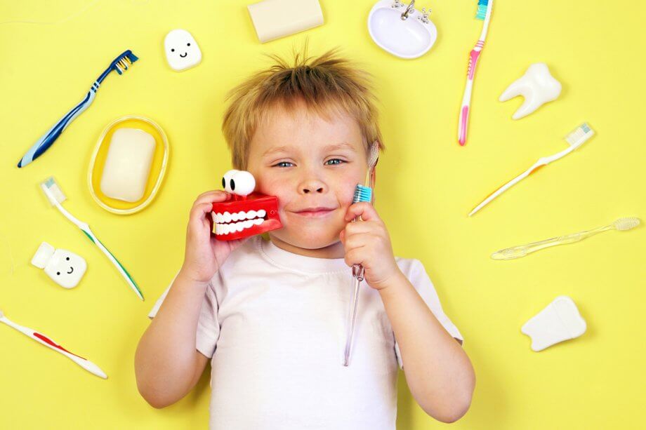 young boy surrounded by toothbrushes and dental hygiene images